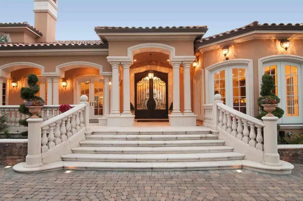 Columned entry of an Italian Palladian estate in Saratoga with a balustrade staircase and ornate iron and glass front doors